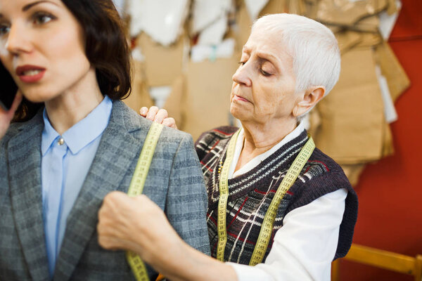 женщина-портной делает измерения
 