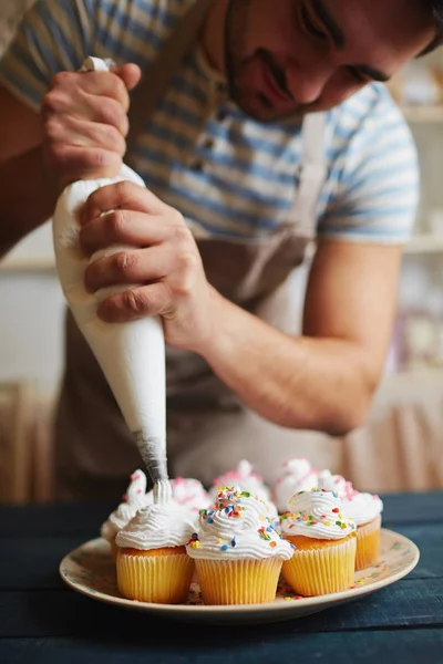 Homem que decora muffins — Fotografia de Stock