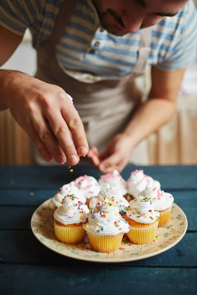 Homem que asperge muffins — Fotografia de Stock