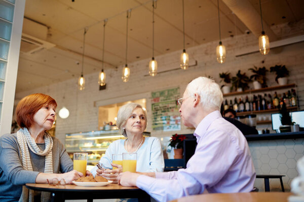 Пожилые люди проводят время в кафе
