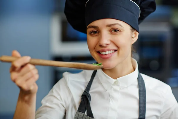 Žena v čepici šéfkuchař ochutnávka potravin — Stock fotografie