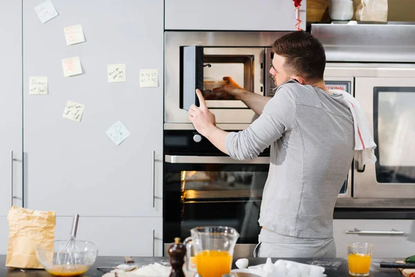 Man taking out container from microwave oven — Stock Photo, Image