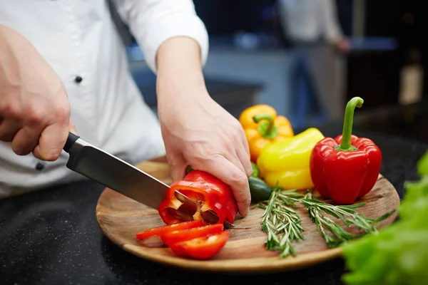 Chef cutting raw peppers — Stock Photo, Image