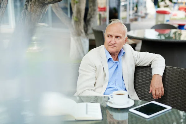 Starszy człowiek siedzi w ulicznej kawiarni — Zdjęcie stockowe
