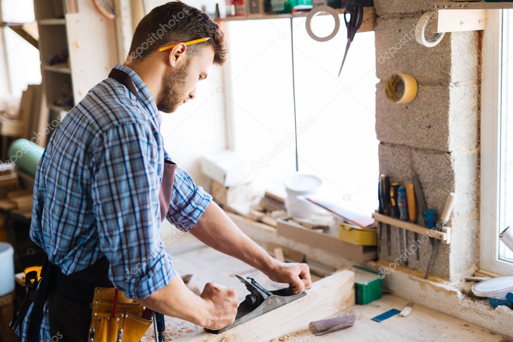 carpenter planing wood on workbench