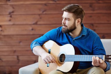 Genç adam ile akustik gitar sakallı.