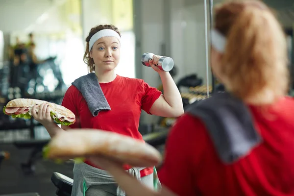 Woman huge with sandwich and dumbbell — Stock Photo, Image