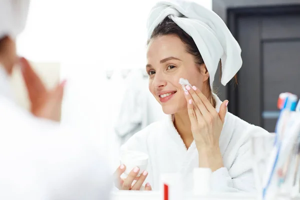 Feminino aplicando creme no rosto — Fotografia de Stock