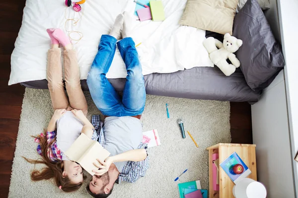 Girl and dad lying on carpet — Stock Photo, Image