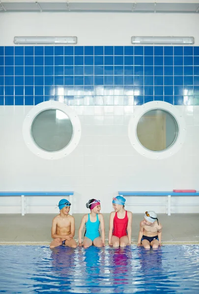 Niños de la escuela sentados en el borde de la piscina —  Fotos de Stock