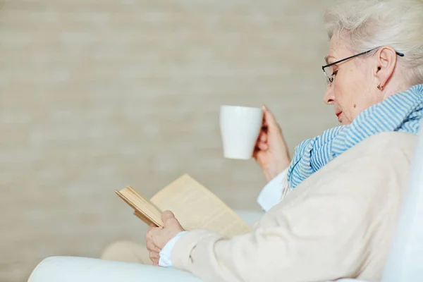 Mujer bebiendo taza de café y leyendo libro — Foto de Stock