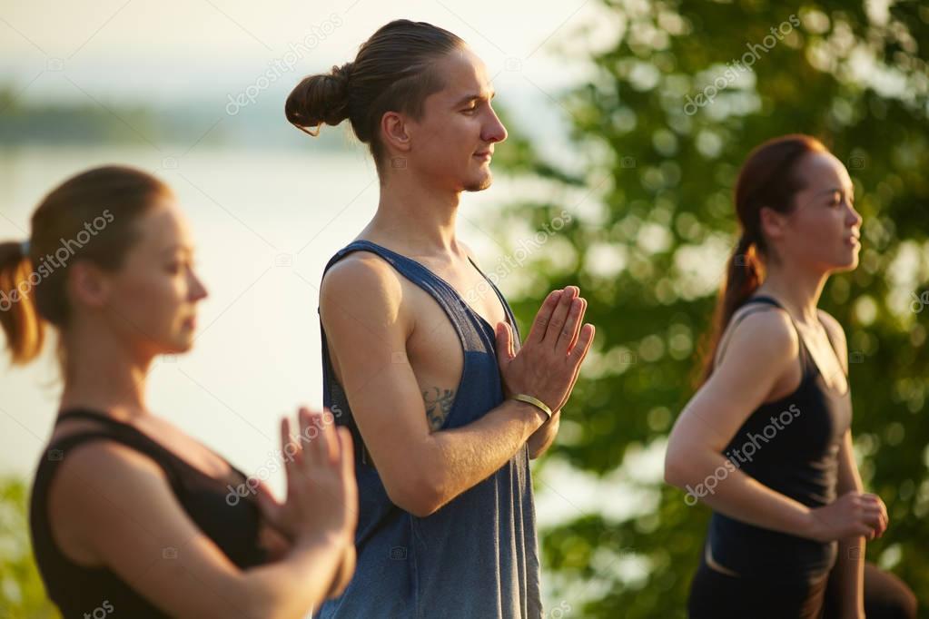 friends holding hands in namaste 