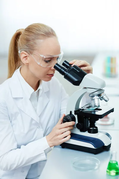 Mujer mirando en el microscopio — Foto de Stock