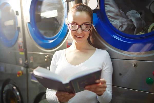 Kobieta czytająca w pralni — Zdjęcie stockowe
