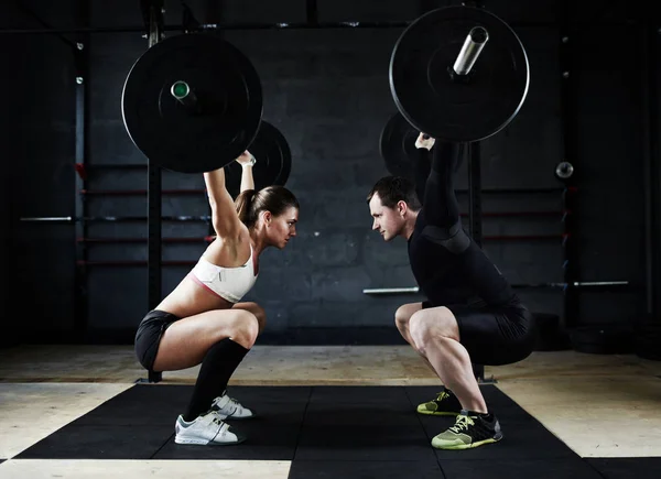 Man och kvinna som utför overhead squats — Stockfoto