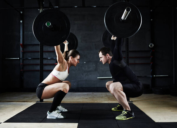 man and woman performing overhead squats