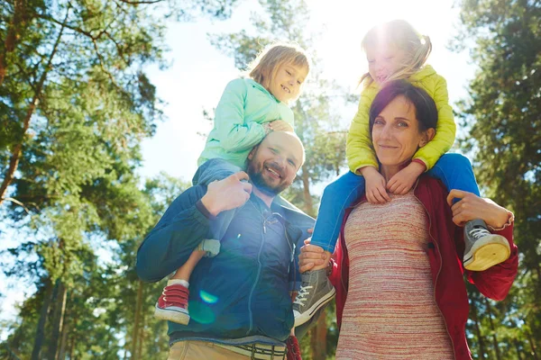 Parents carrying little daughters on shoulders — Stock Photo, Image