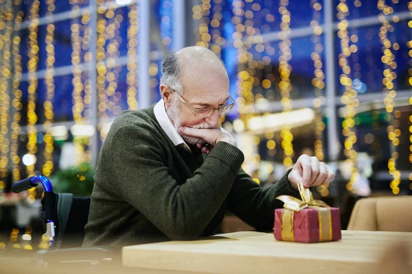 ギフト ボックスを見ている年配の男性 — ストック写真