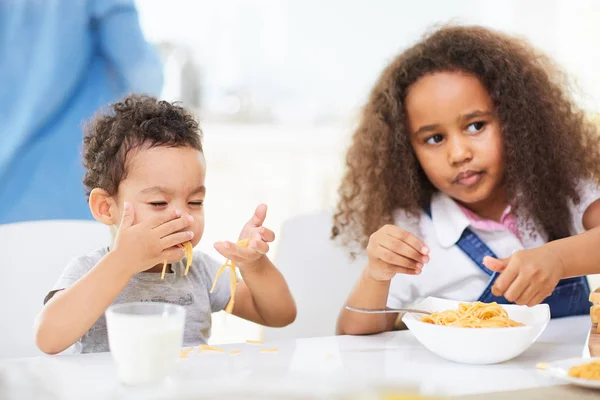 Jongen en mooie zus zitten aan tafel — Stockfoto