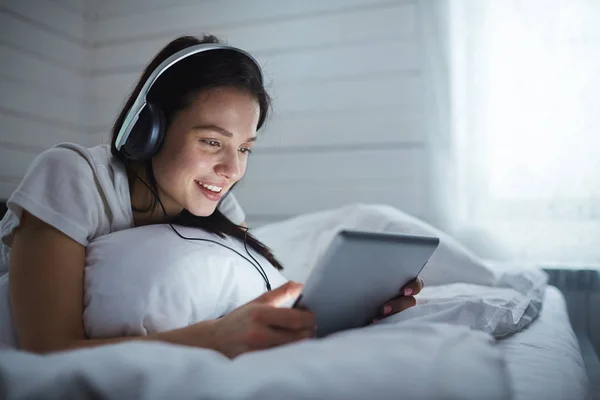 Mädchen mit Kopfhörern schaut in Touchpad — Stockfoto