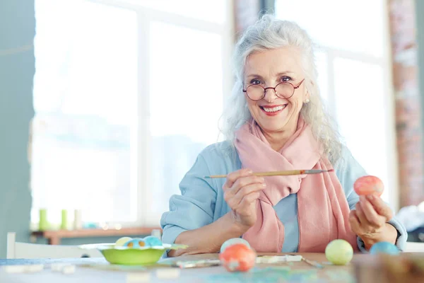 Mujer de pelo gris pintando huevos — Foto de Stock