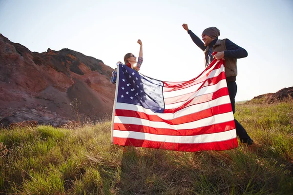 Jovens alegres acenando grande bandeira — Fotografia de Stock