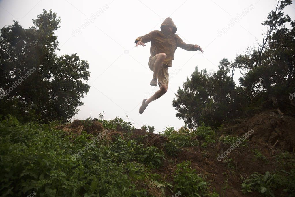 hiker jumping off the green hill