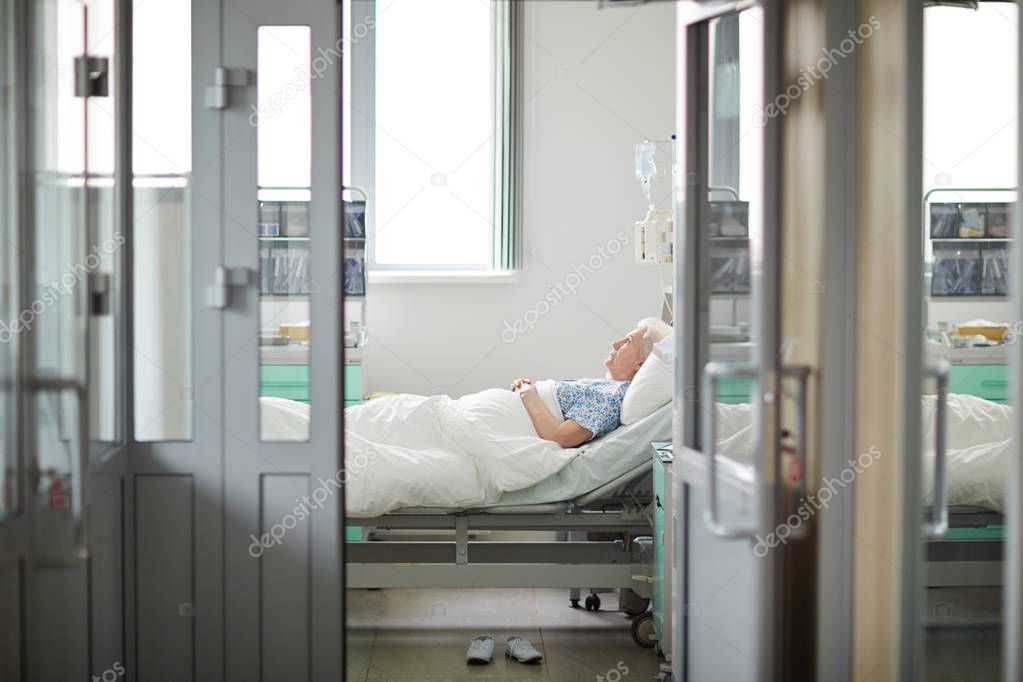 old woman lying on bed in room