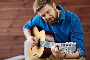 Genç adam ile akustik gitar sakallı.