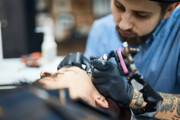 Tattooer drawing on face — Stock Photo, Image