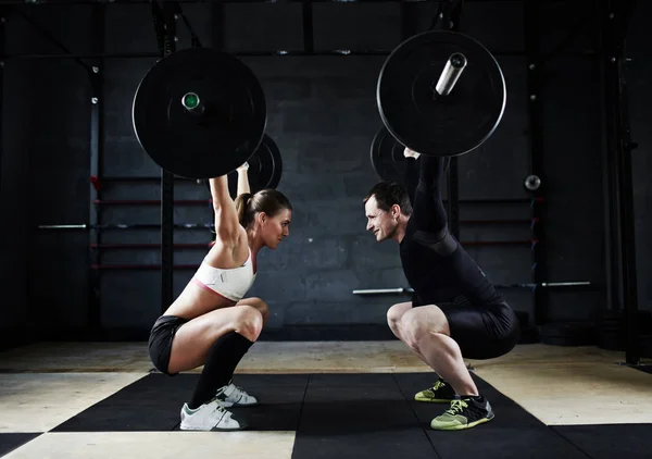 Man and woman holding  huge barbells — Stock Photo, Image