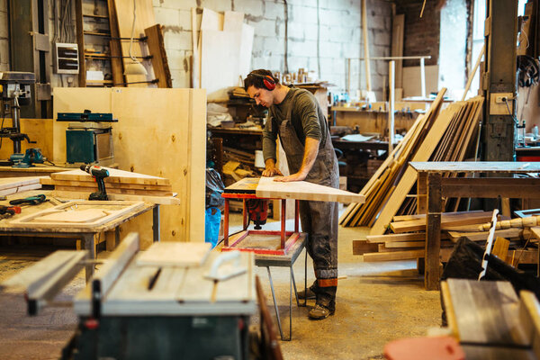 Деревянный рабочий смотрит на деревянную доску
