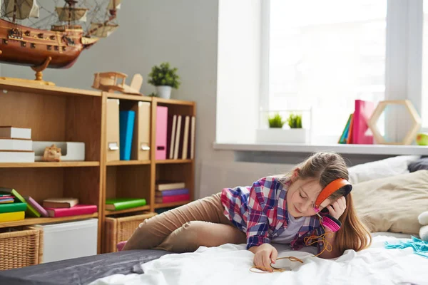 Mädchen mit Kopfhörern auf dem Bett — Stockfoto