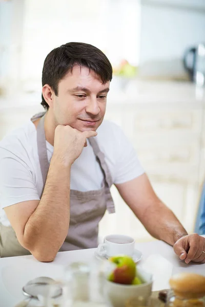 Man in apron sitting at table — Stock Photo, Image