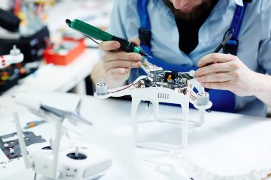 Tanınmayan adam elektrik akımı devre kartı sökülüp dronun tablo bakım salonu multimetre aracını kullanarak test closeup çekim