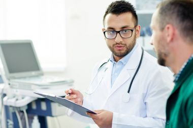 Yougn doktor whitecoat ve yeni ilaç almak onun hasta açıklayan gözlük