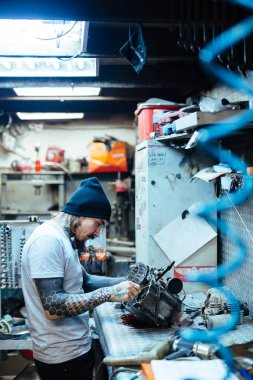 Yan görünümü kırık motor atölyesinde tamir modern dövmeli adam portresi