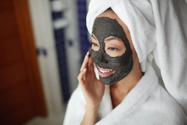 シャワーの後治療の美しさのルーチンの中にフェイス マスクを適用する 鏡で見ていると笑みを浮かべて美しいアジアの女性の肖像画 — ストック写真
