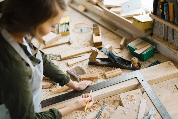 Ölçüm yardımı ile çelik çerçeve Meydanı ve atölye kurşun kalemle işaretleme kendine güvenen genç craftswoman profil görünümü