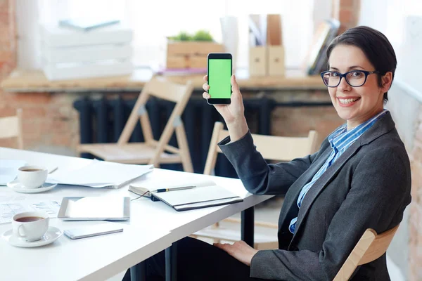 Zufriedene Geschäftsfrau Sitzt Arbeitsplatz Und Zeigt Touchscreen Des Smartphones — Stockfoto