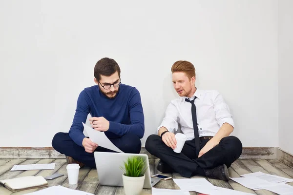 Porträtt Två Affärsmän Sitter Korslagda Ben Golvet Office Pratar Använder — Stockfoto