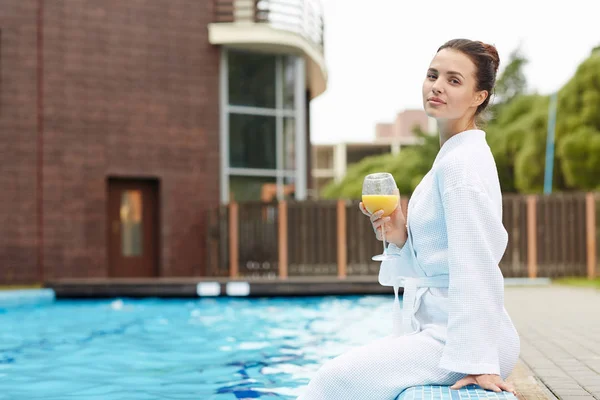 背景にホテルとリゾートのスイミング プールでリラックスしたバスローブの若い女性 — ストック写真