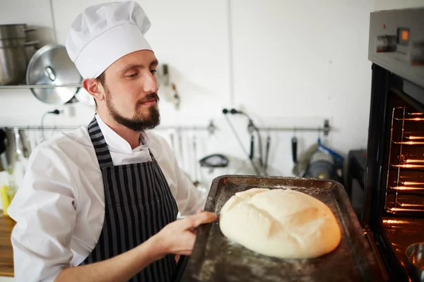 Genç Baker Ile Ham Somun Ekmek Fırın Içine Koyarak Tepsi — Stok fotoğraf