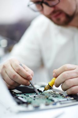 Tornavida ve kırık pats için seyir cımbız ile sökülüp dizüstü bilgisayarda çalışma gözlüklü adam closeup çekim