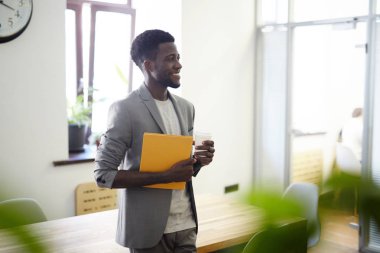 Klasör ve içki yaslanarak agaist Masası ofiste mutlu genç uzman