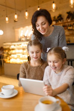 Modern genç kadın ve İkiz kızları kafede boş zaman harcama touchpad ile