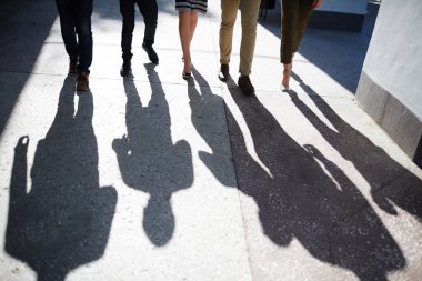 İki iş kadınları ve üç işadamı cadde boyunca, üzerinde eski püskü asfalt yansıtan onların gölgeler yürüyüş