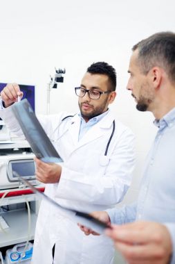 adiologist ve asistanı kliniklerde x-ray testlerin sonuçlarını tartışıyor