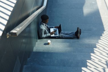 Laptop ve gölgede merdivenlerde oturan smartphone ile meşgul satıcısı