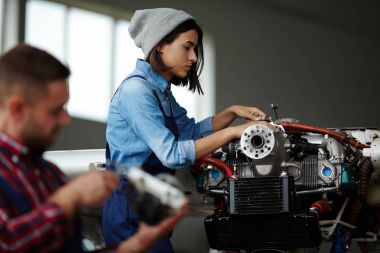 Yan görünümü motor parçaları yanında, hem giyen işçi üniforma ve tulum adamla atölyesinde tamir modern kadın portresi